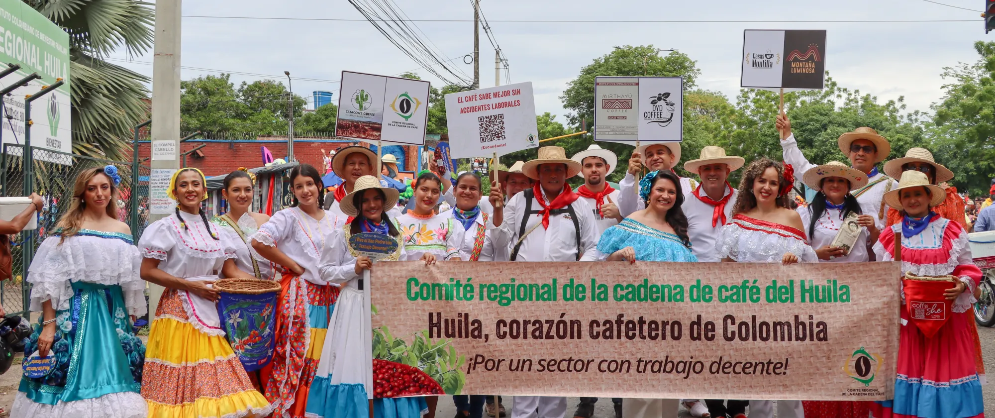 Integrantes del Comité Regional de la Cadena de Café, productores cafeteros y representantes de OIT, posan en el desfile folclorico departamental en la ciudad de Neiva, Huila, usando trajes típicos con el cartel “Comité Regional de la Cadena de café del Huila. Huila, corazón cafetero de Colombia. ¡Por un sector con trabajo decente!”