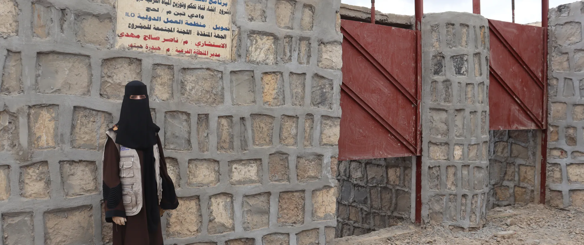 a female contractor standing in front of a project signboard
