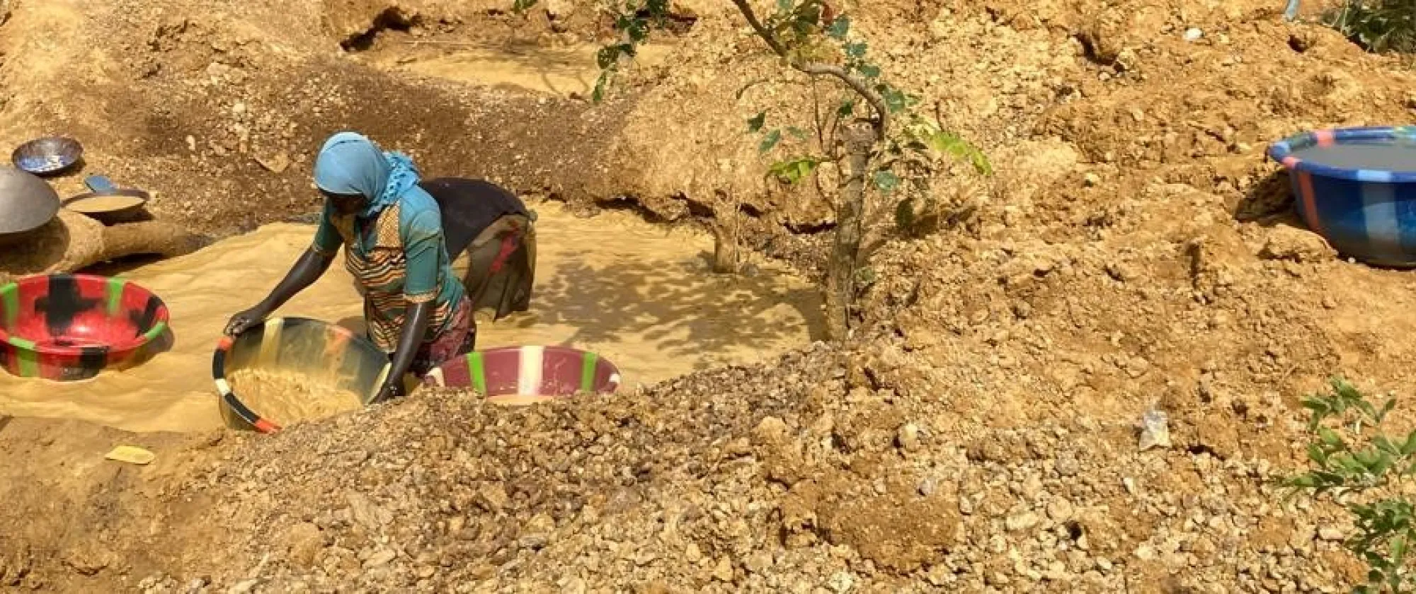 Women is inside water in an artisanal gold mining and clears stones