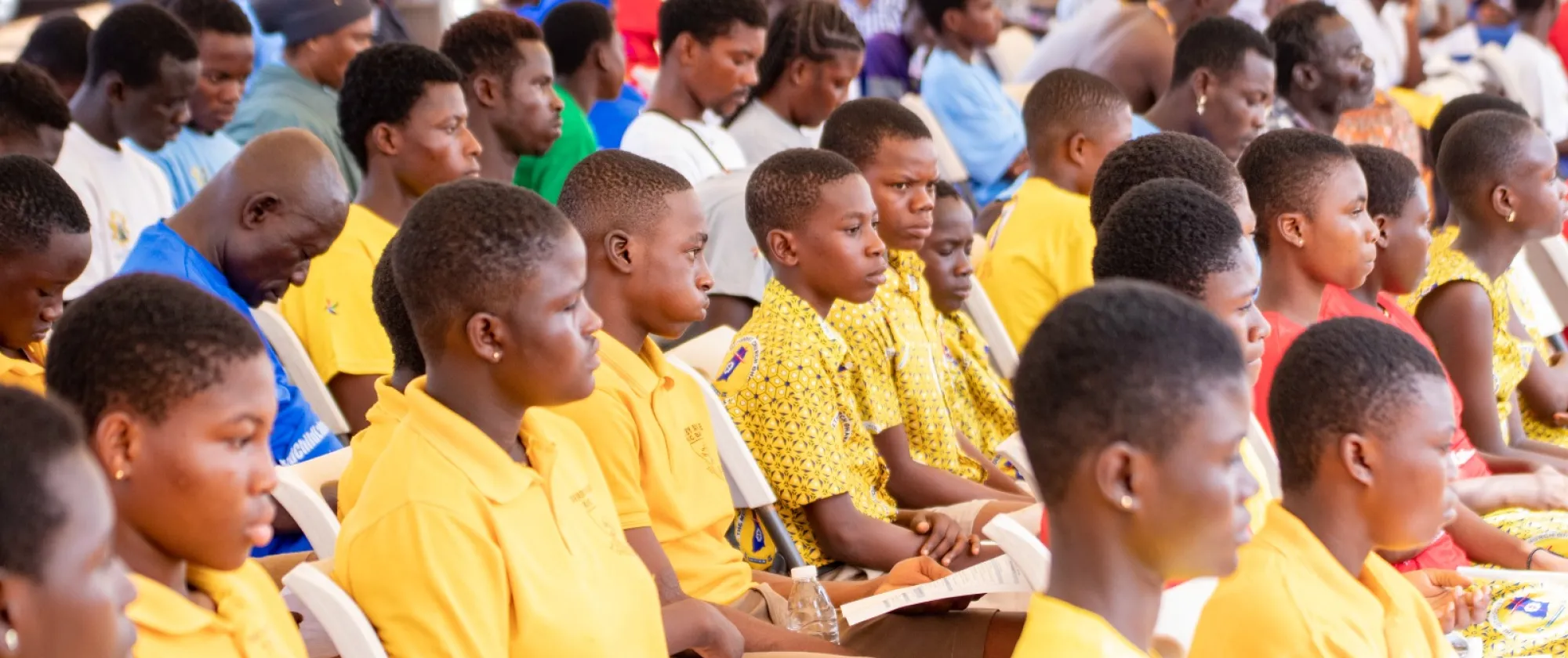 Children listen attentively in yellow uniforms