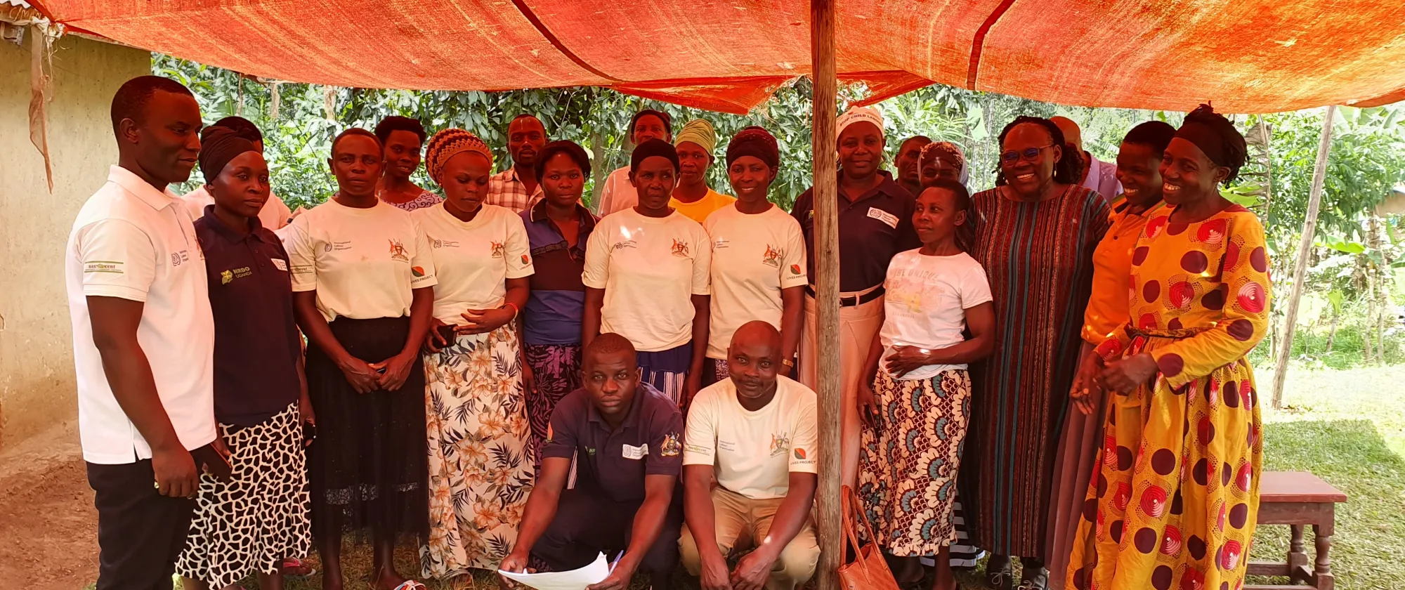 Community members pose for a picture under an orange tent