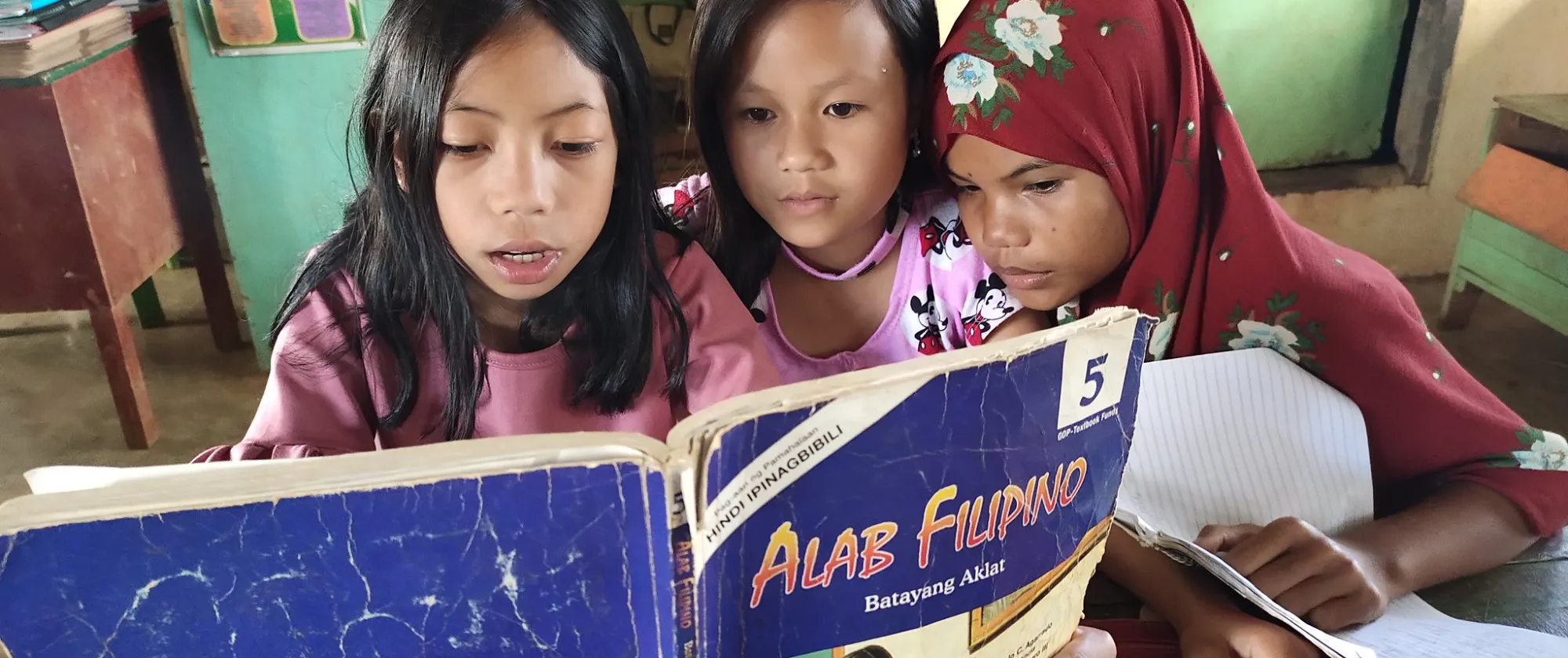 A group of girl students in a school in Maguindanao browse through their Filipino textbook