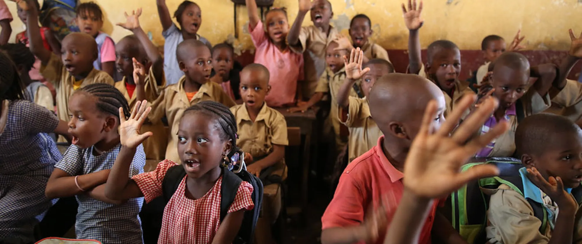 Children raises their hands to answers a teachers questions at the Wodia Berete School in Conakry, Guinea