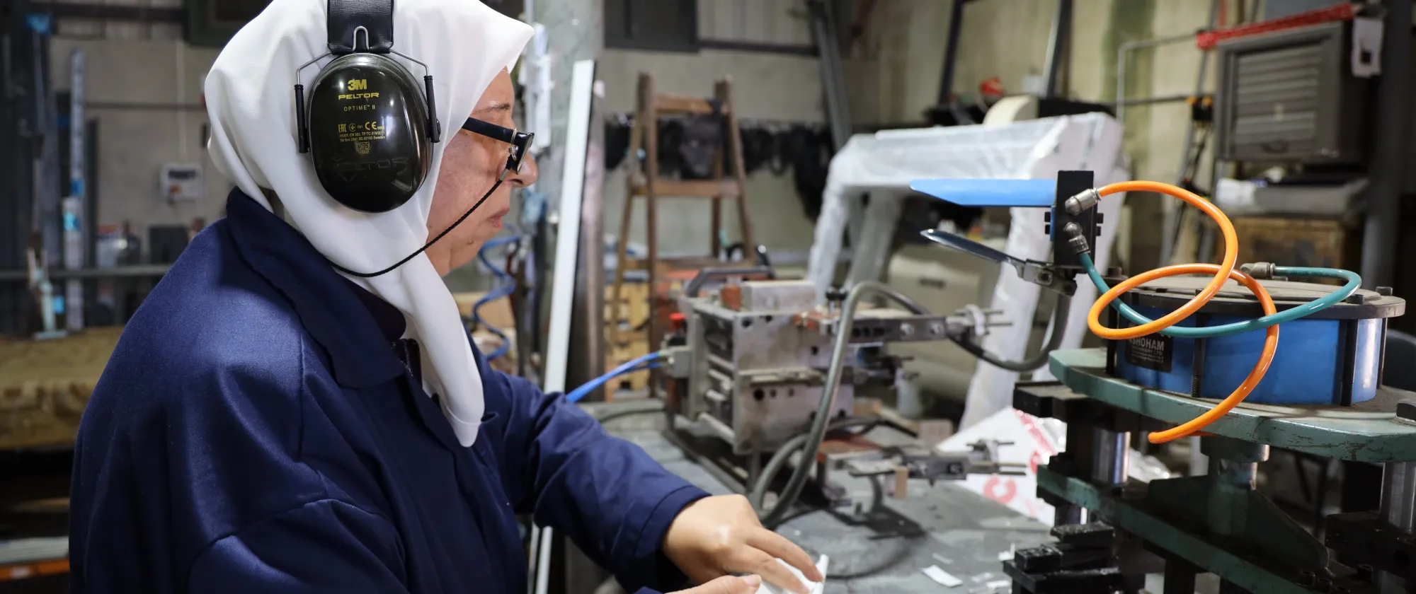 A Palestinian woman with headphone working in an aluminium workshop in Nablus, occupied Palestinian territory