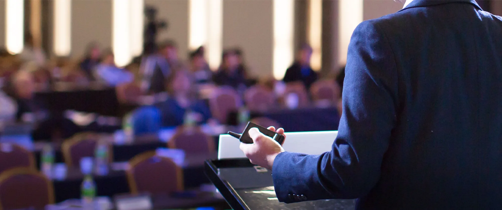 A businessman giving a speech to a defocused blurred audience in a conference hall