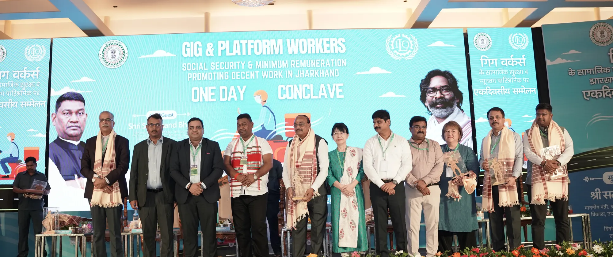 Panelists standing on the stage in front of a digital backdrop