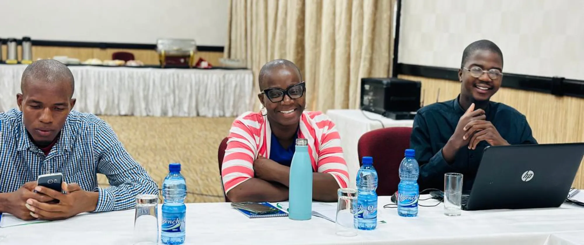 people seat at a table with water bottles and smile