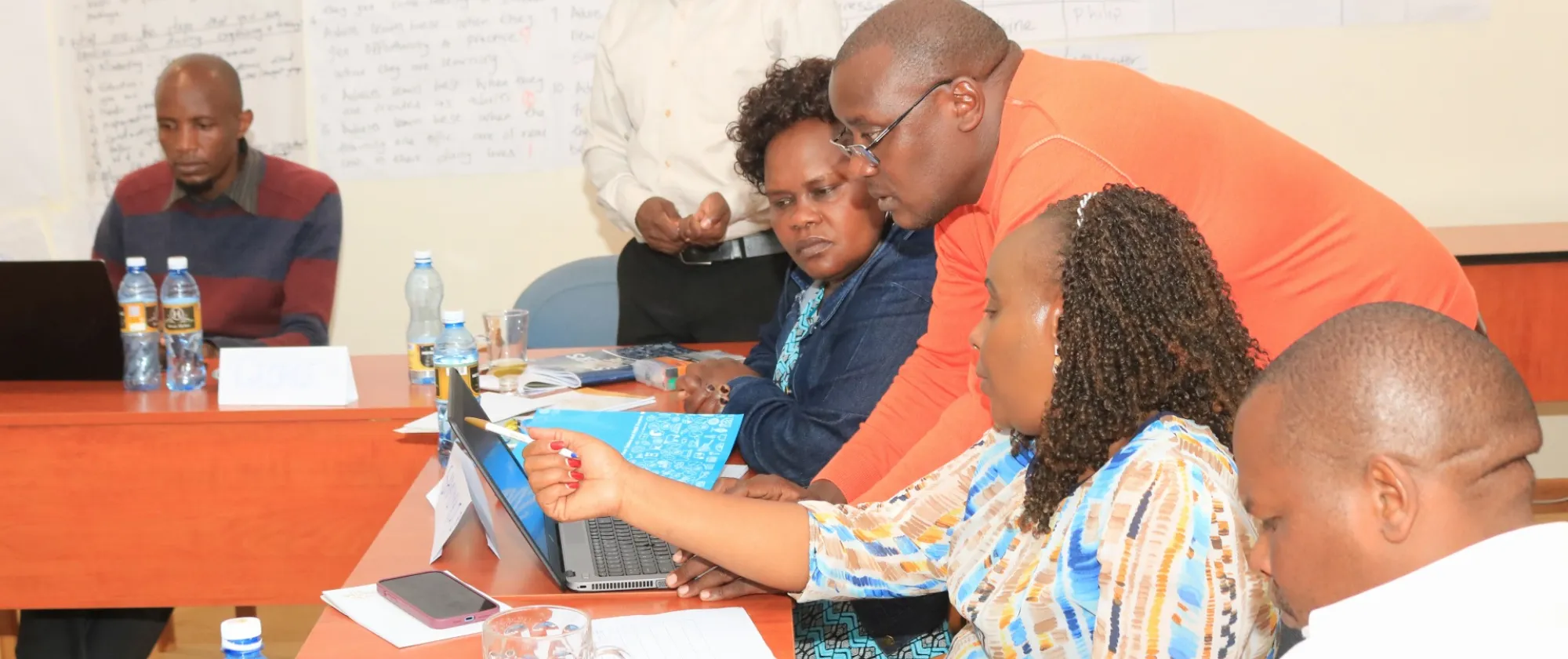 Participants of a training help each other, while looking at a laptop computer