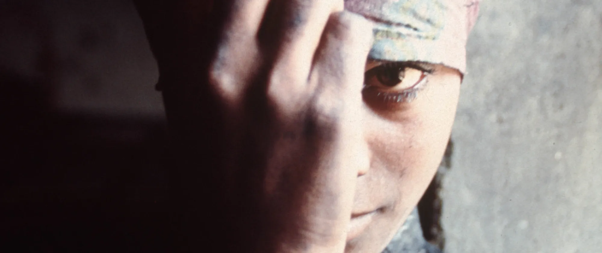 Portrait of young woman hiding behind her hand and scarf