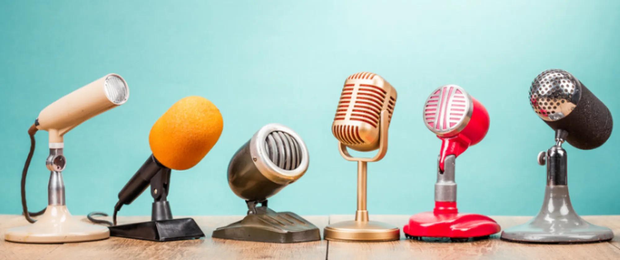 Microphones of many colours with a green background