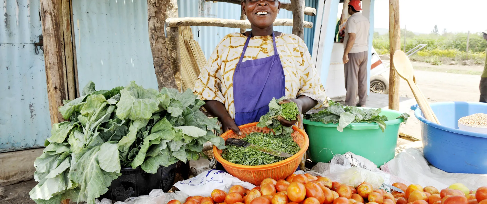 woman behind her stall selling vegetable on a market