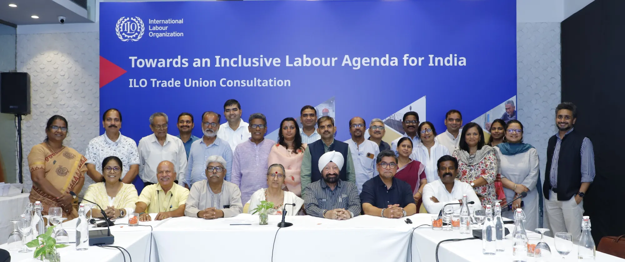 Men and women standing together in front of a blue back drop