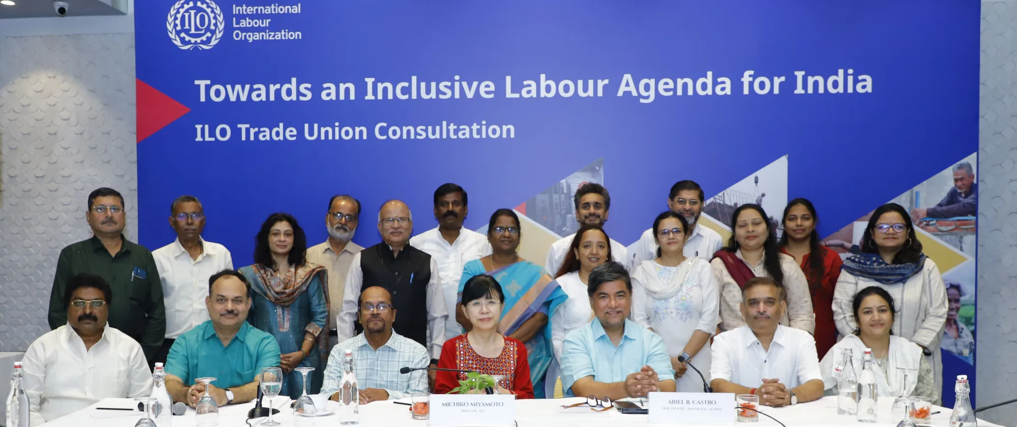Men and women standing together in front of a blue back drop