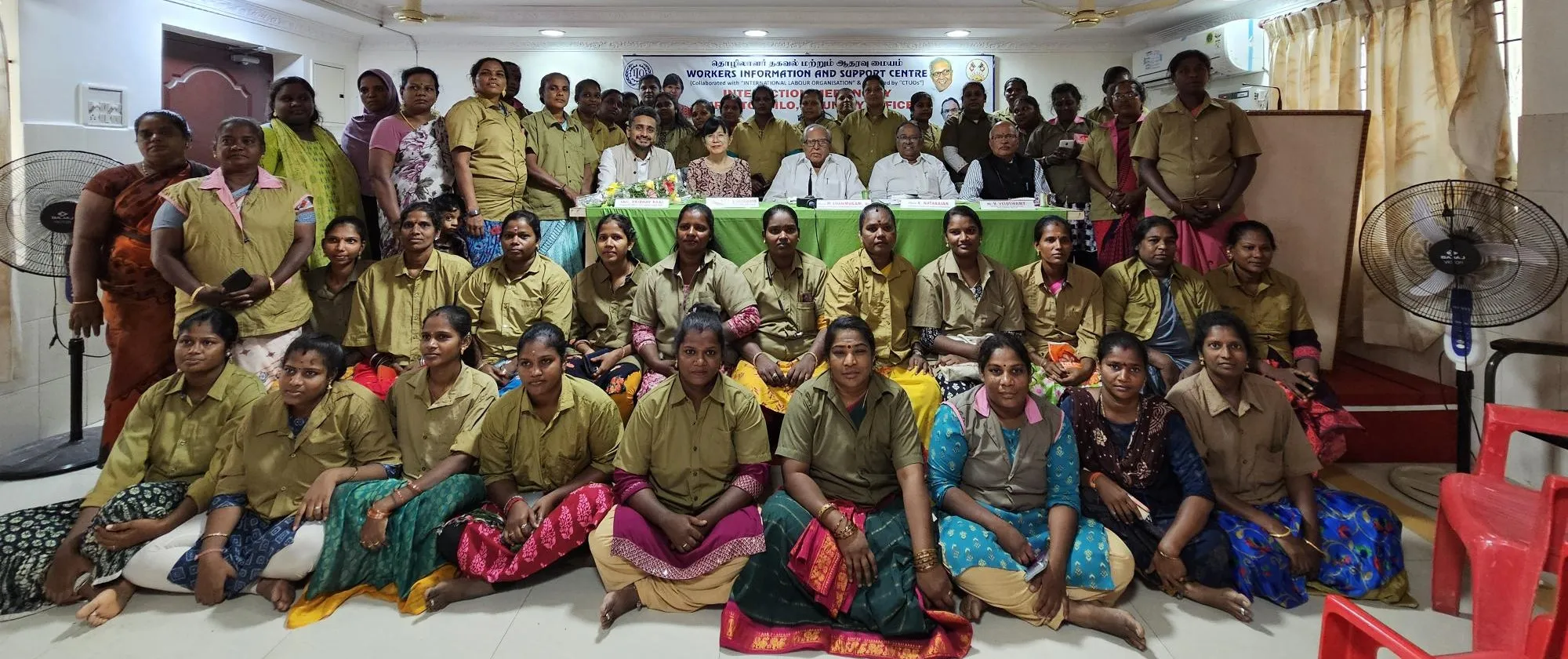 Women and men posing together in a conference hall for a group photo