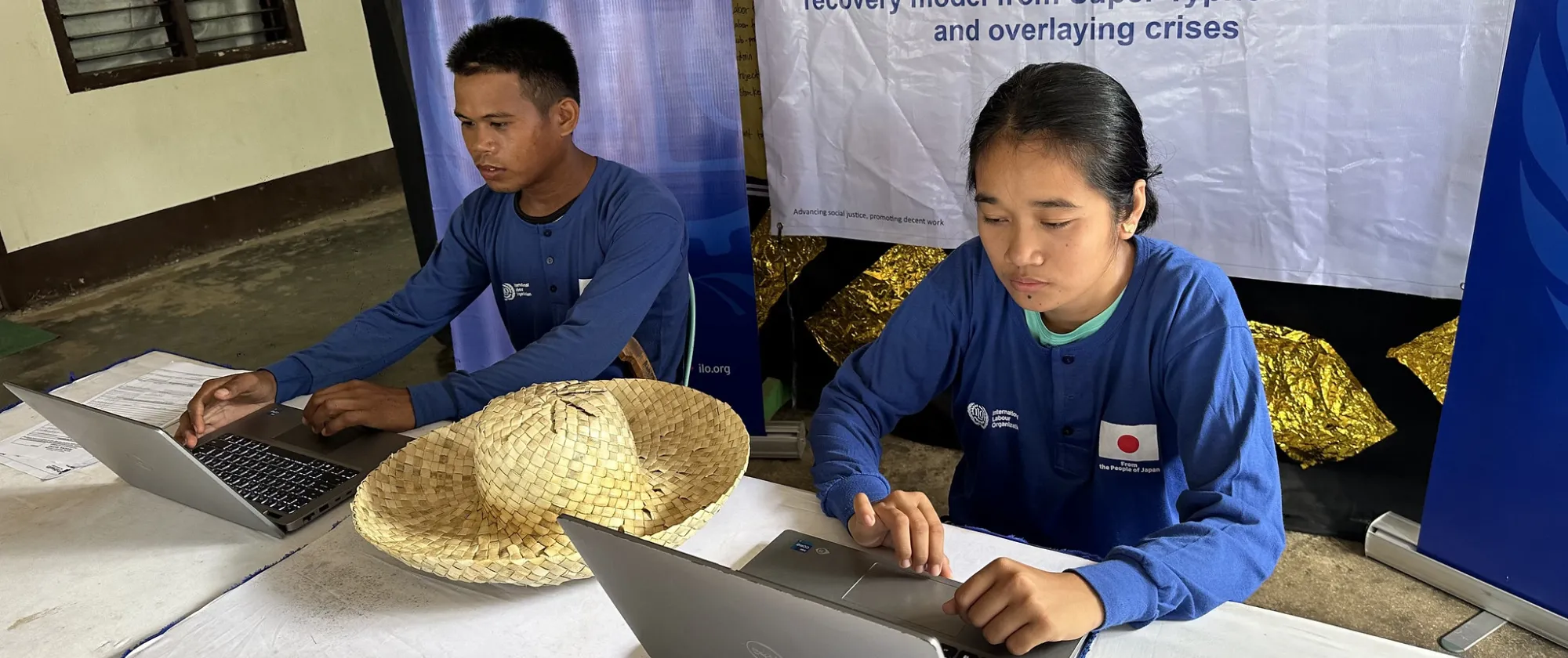 male and female workers use a laptop to register online for social protection