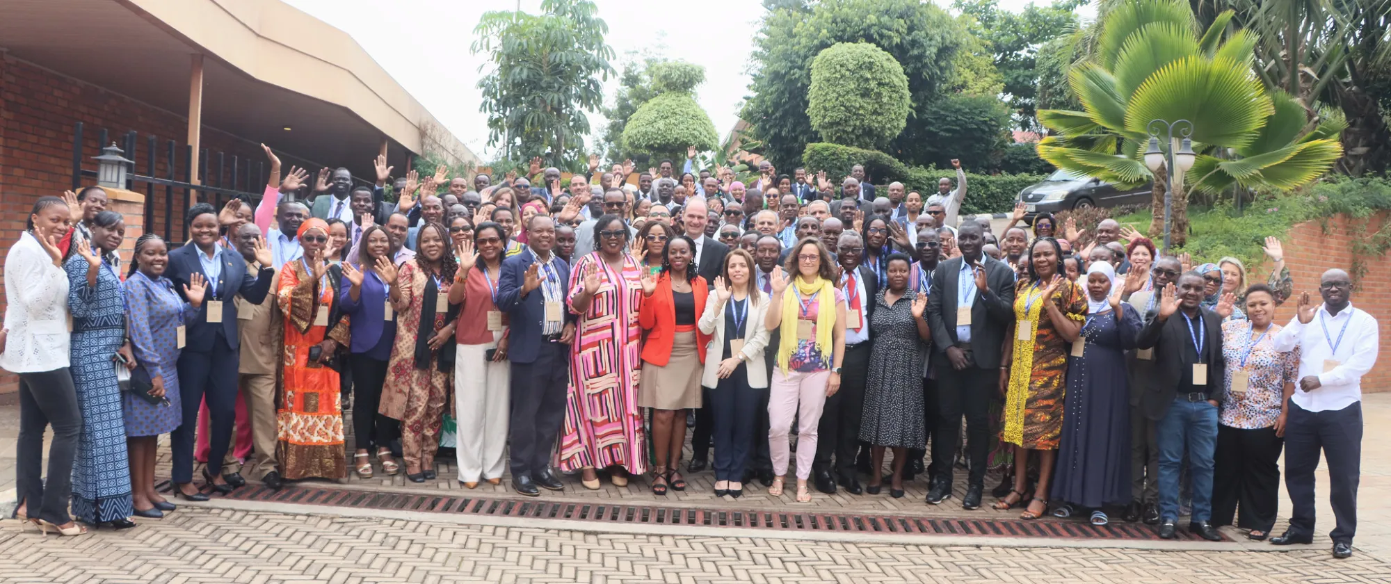 Participants to the regional academy on fundamental principles and rights at work pose for a group photo, they are around 100 and some of them raise their hand in the photo