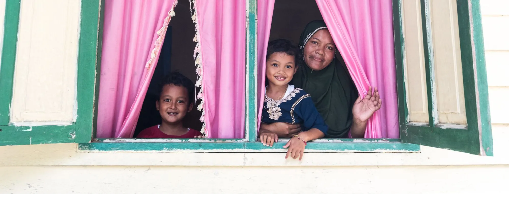 a mother with 2 kids looking out from a big window