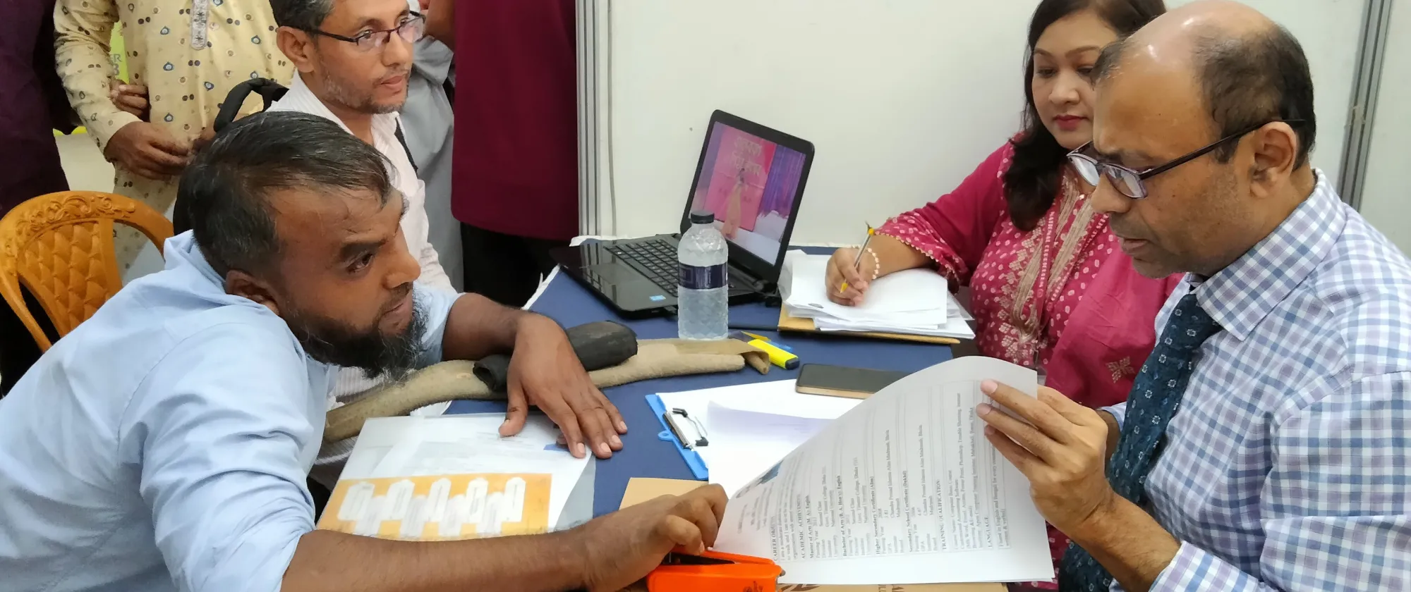 A person with physical disabilities speaks with a prospective employer at a job fair held in Chattogram, Bangladesh