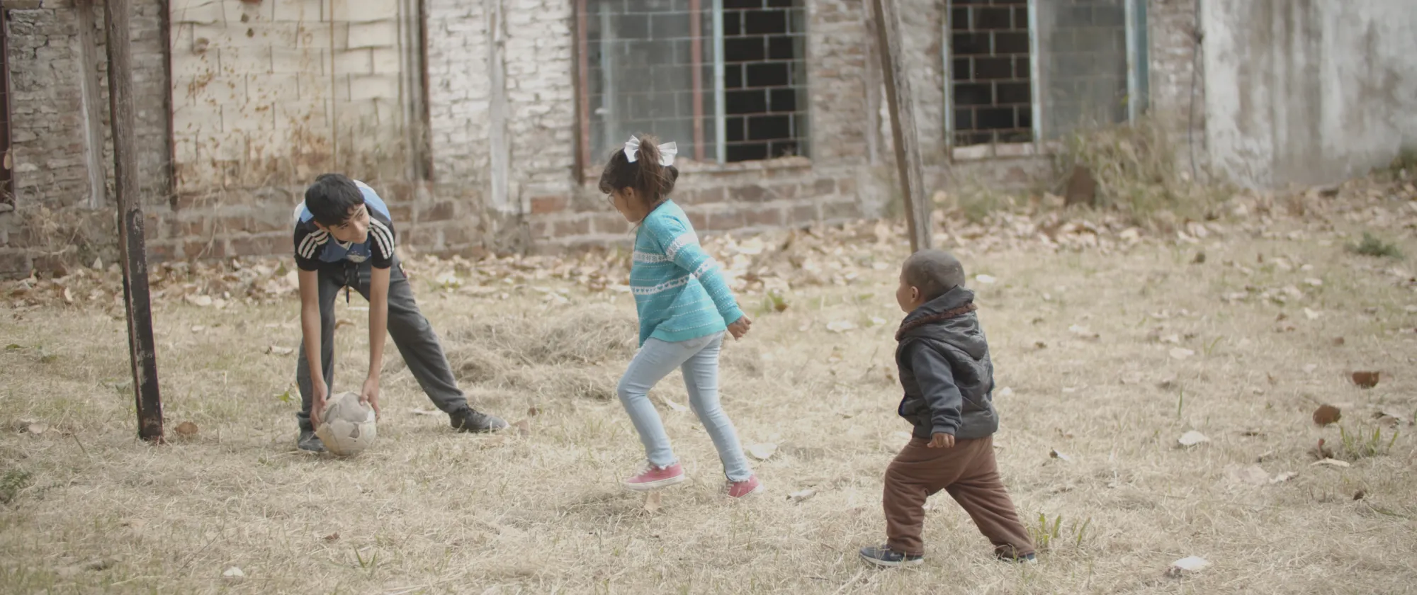 Un niño y dos niñas juegan juntos con una pelota.