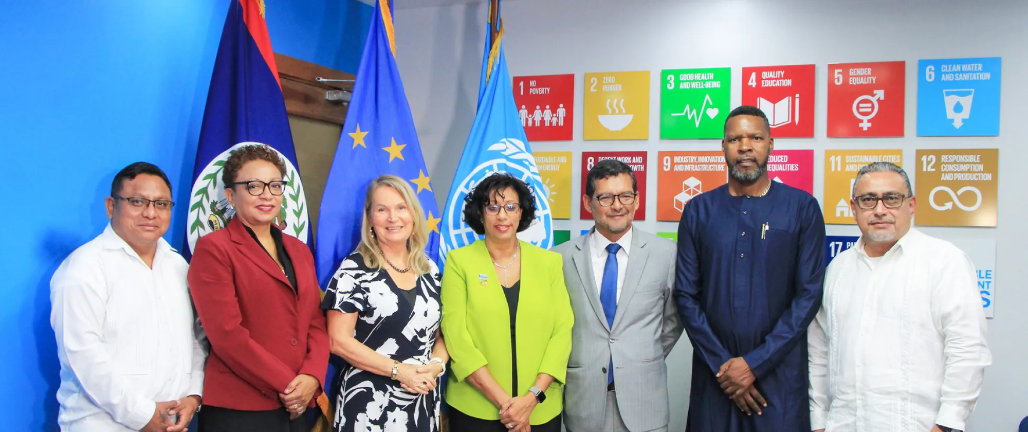 A group of people standing in front of flags and SDG banner