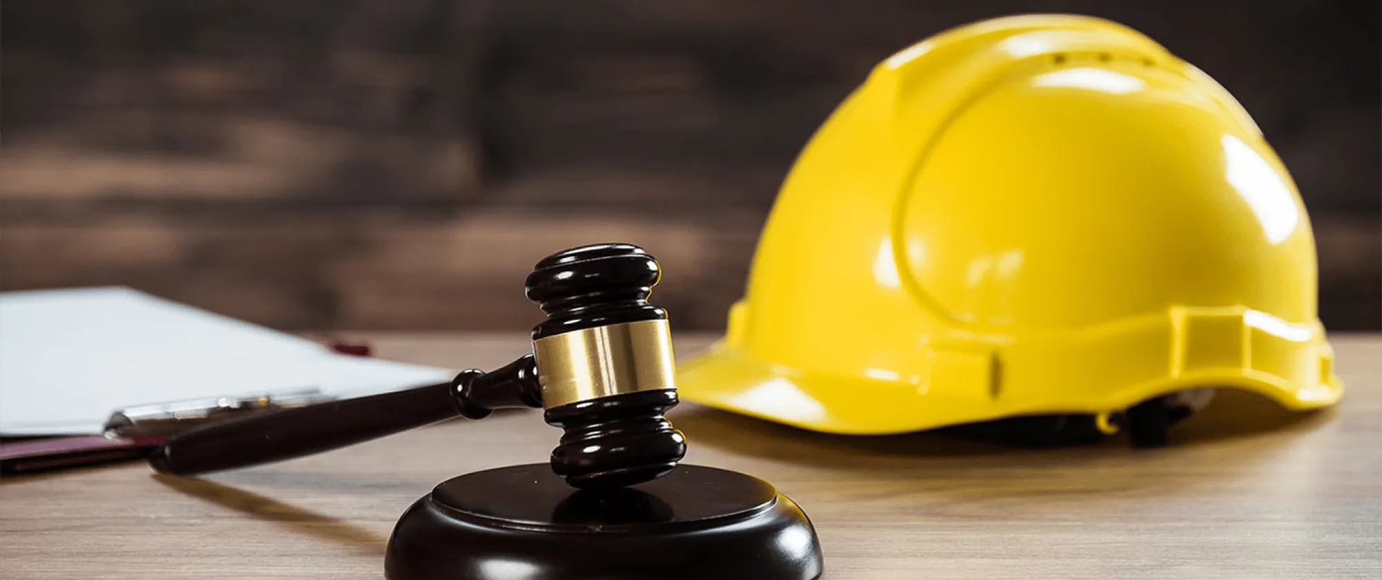 A brown gavel and a yellow safety helmet