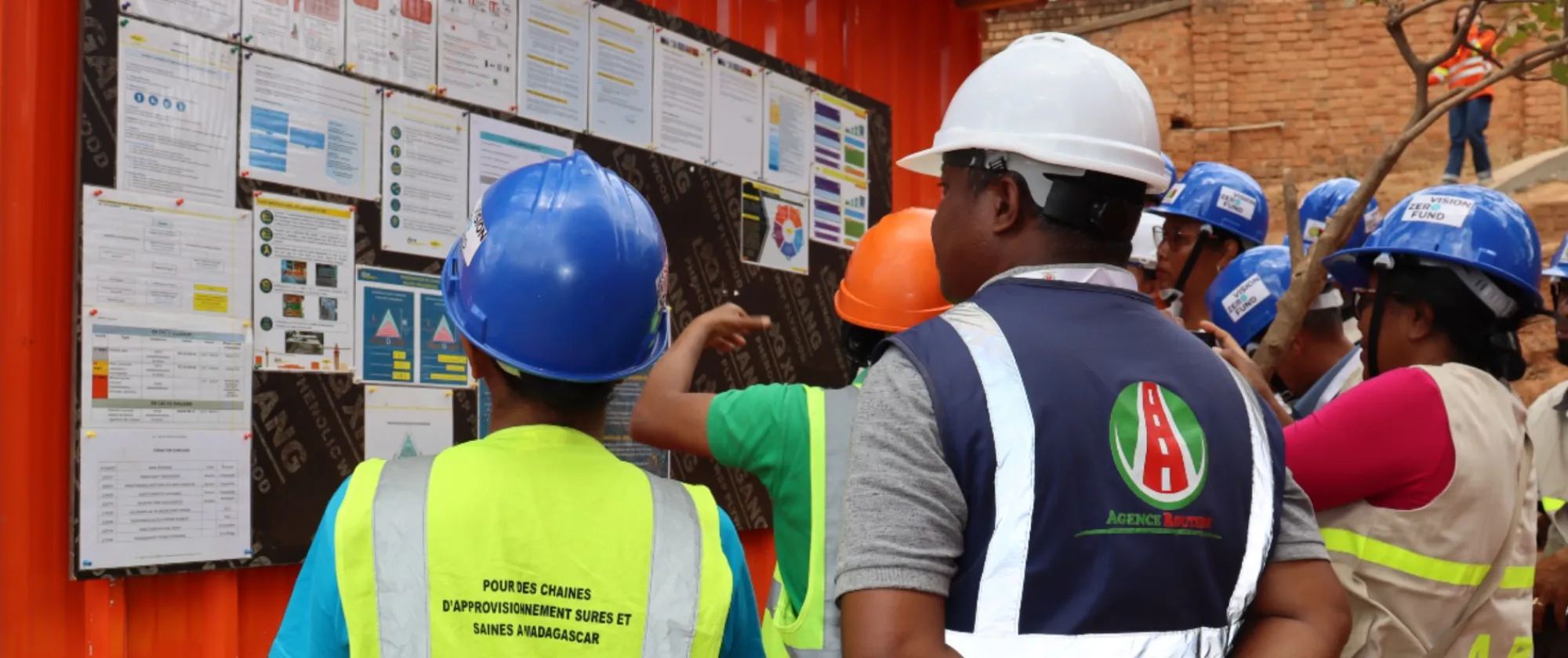 Group of worker on construction site looking at a board.