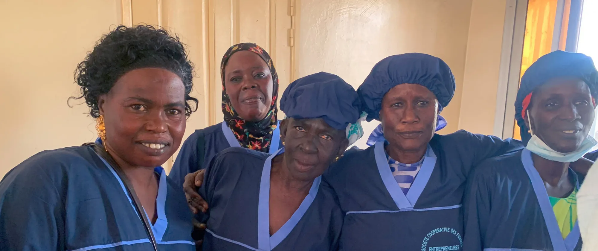  Membres d'une coopérative de femmes posant ensemble, vêtues de tenues de travail bleues, symbolisant leur engagement dans une activité collective et solidaire.