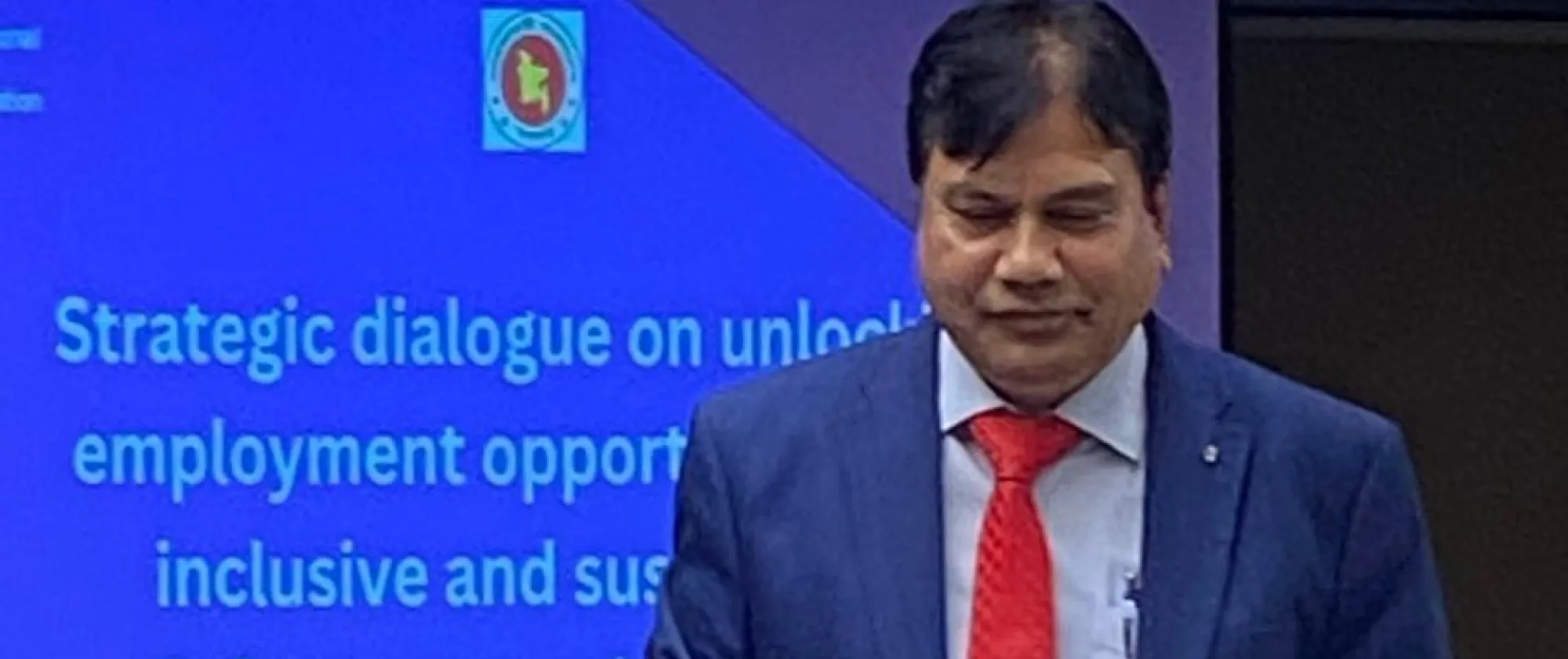 A man in front of a backdrop that reads unlocking employment opportunities for inclusive and sustainable infrastructure initiatives