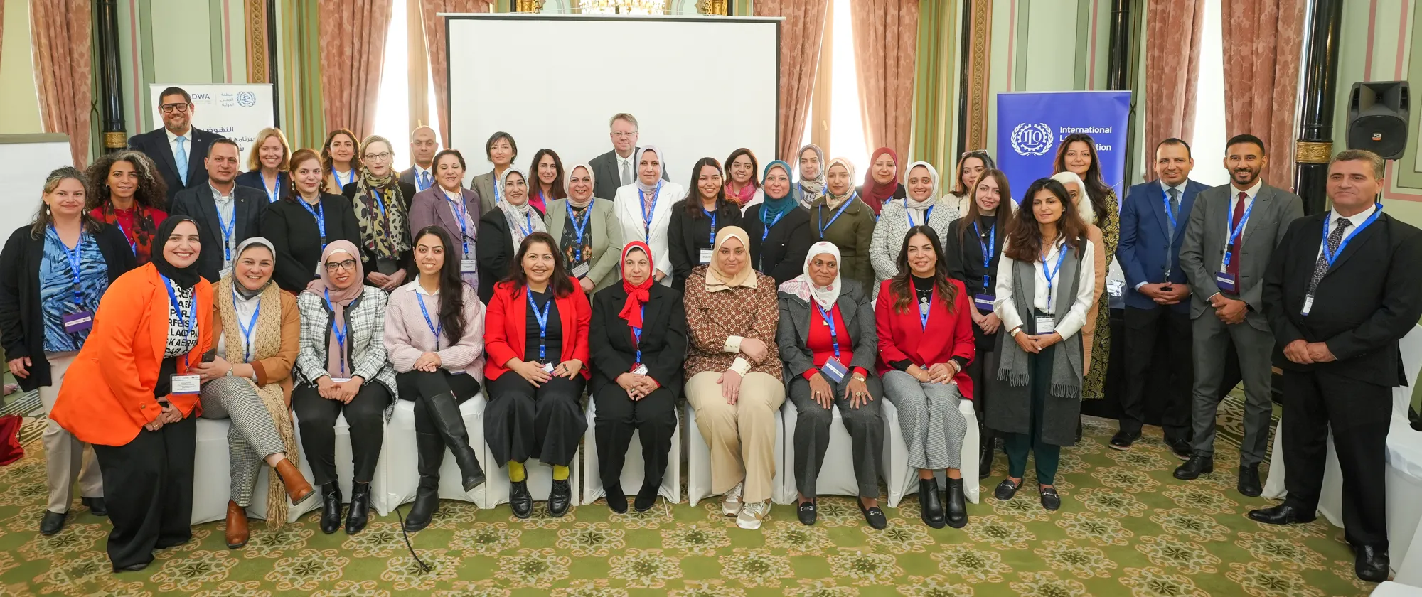 Group of participants pose for a photo with the ADWA' project and ILO roll-ups.