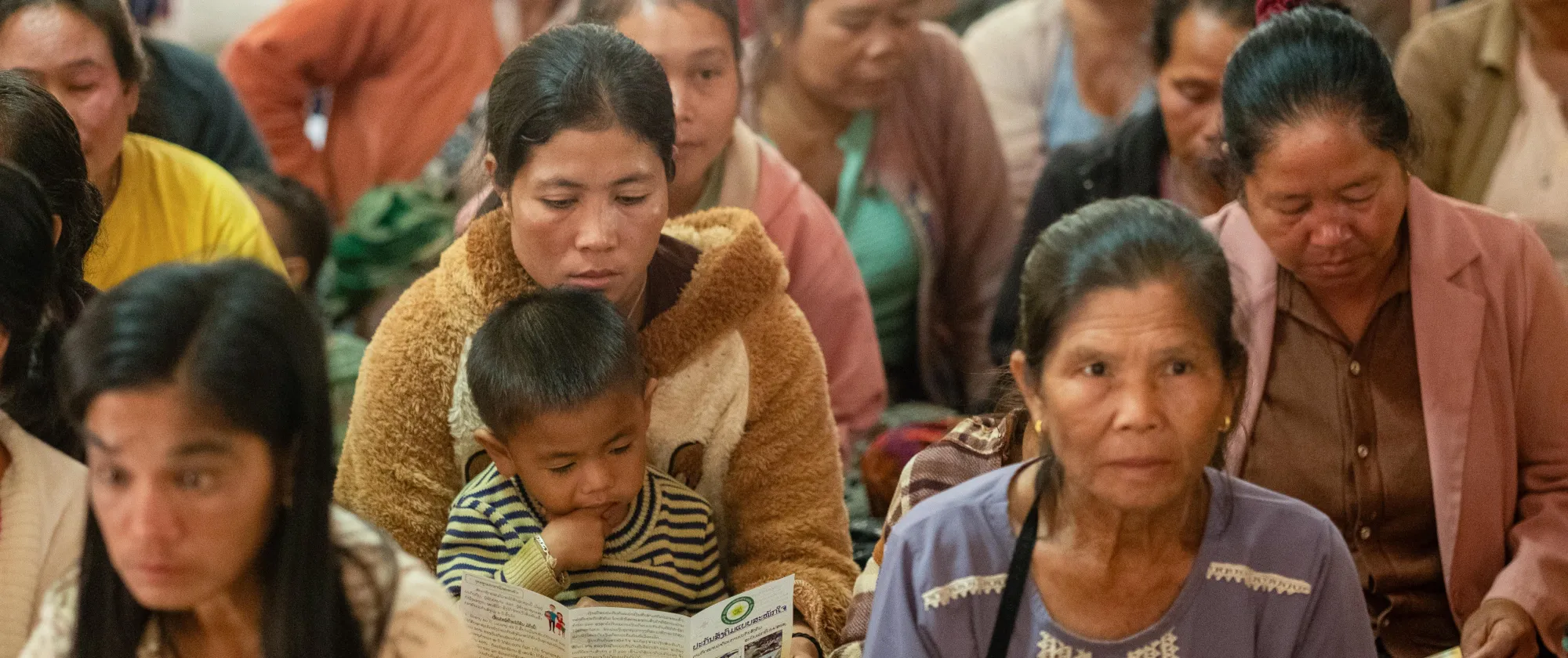Women, men and children sit together. 