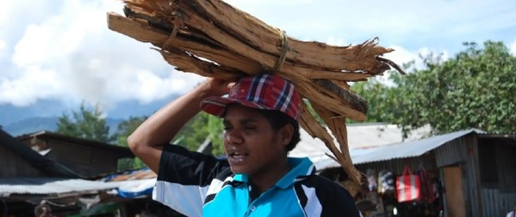 A Papuan woman carries wooden slats on her head at a market