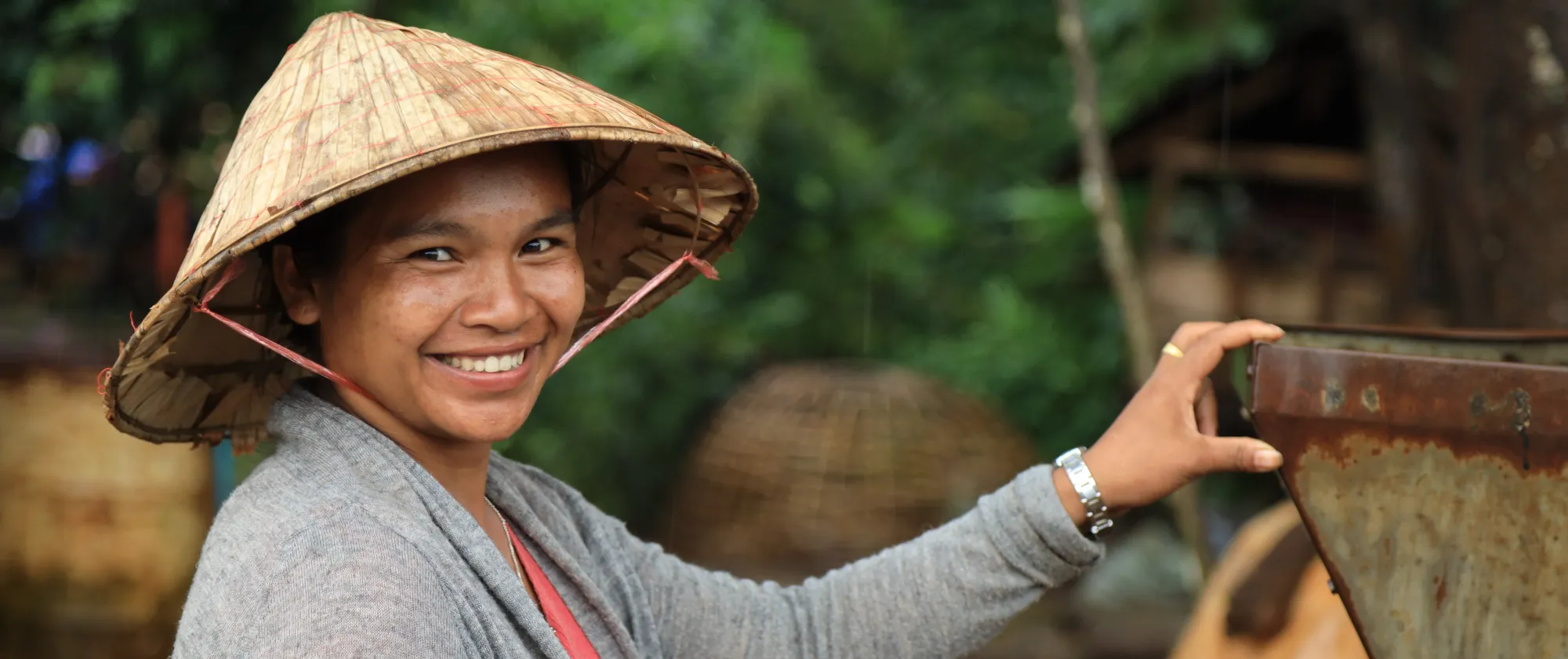 A woman, wearing a straw hat, smiled.