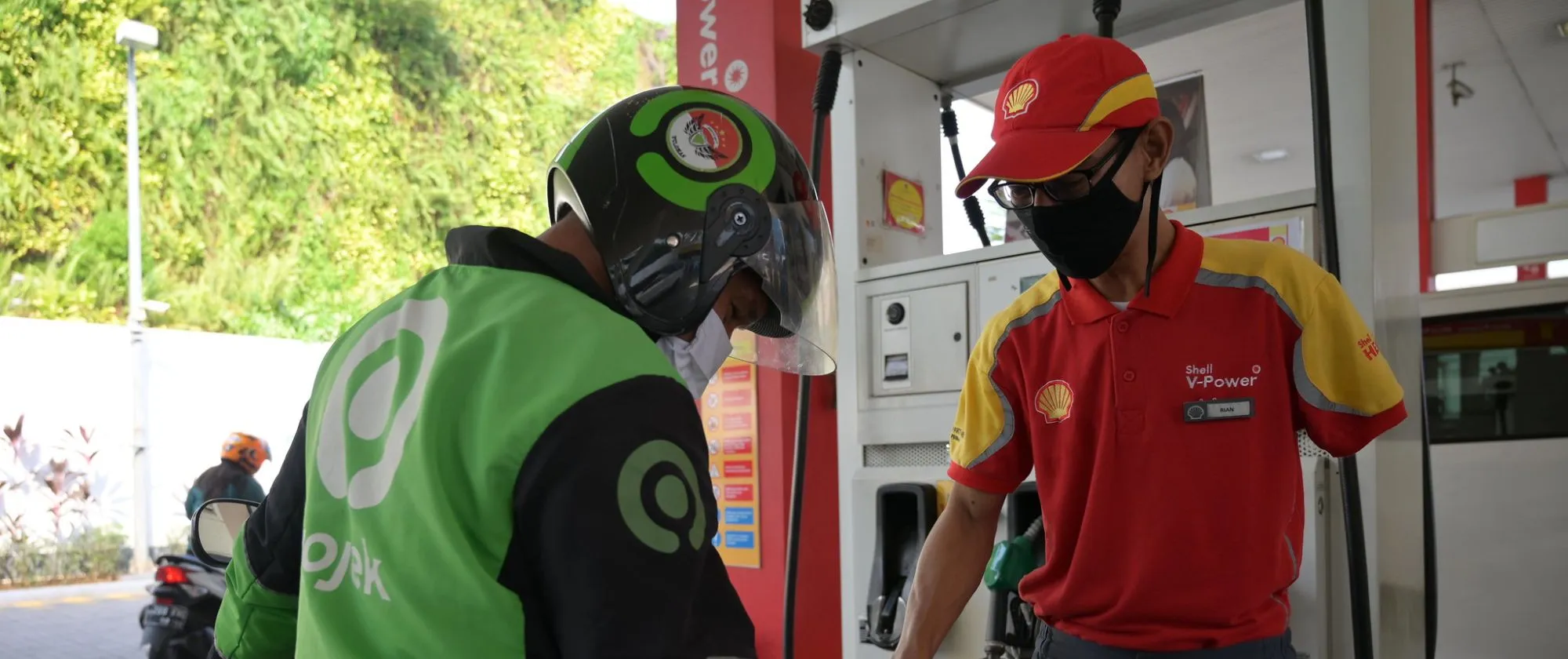 a male disabled worker in a gas station refilling fuel into a motorcycle