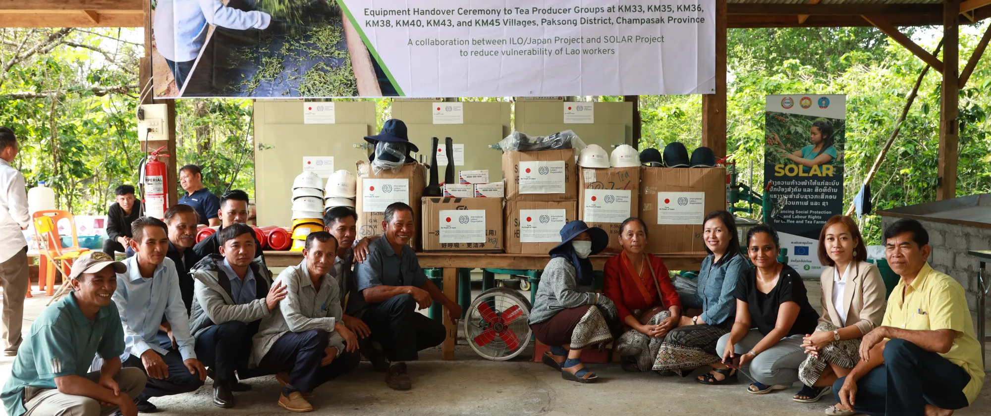 A group photo of tea farmers sitting in a half circle. 