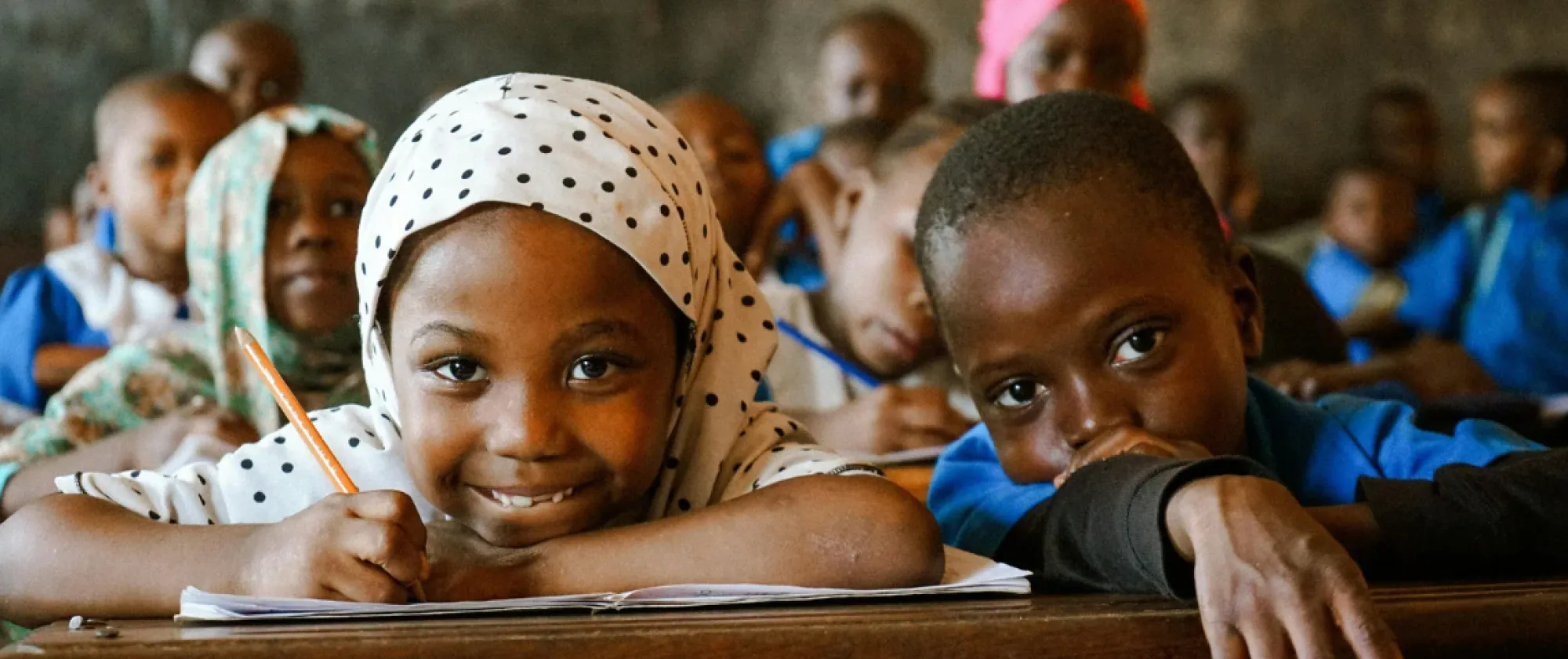 A girl and a boy seat a school with a smile