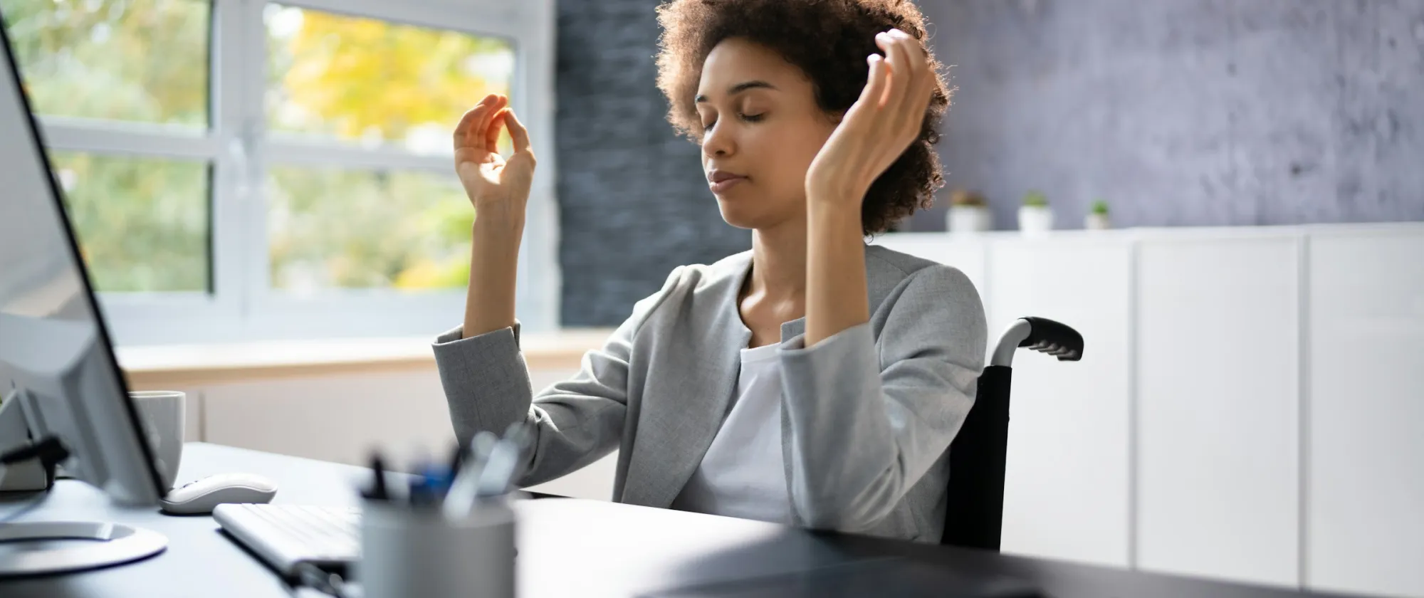 A woman meditating while sitting at a desk