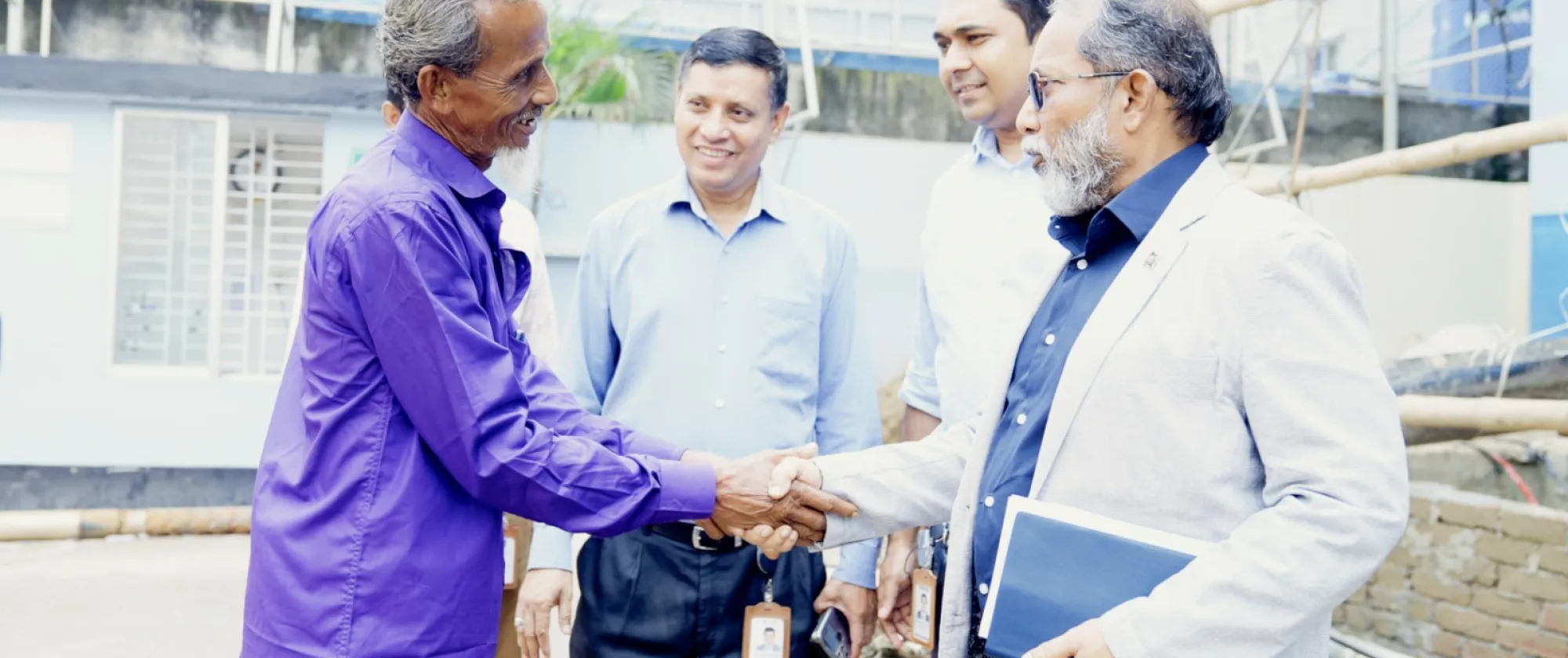 A man greets officials of the garment factory that employed his son