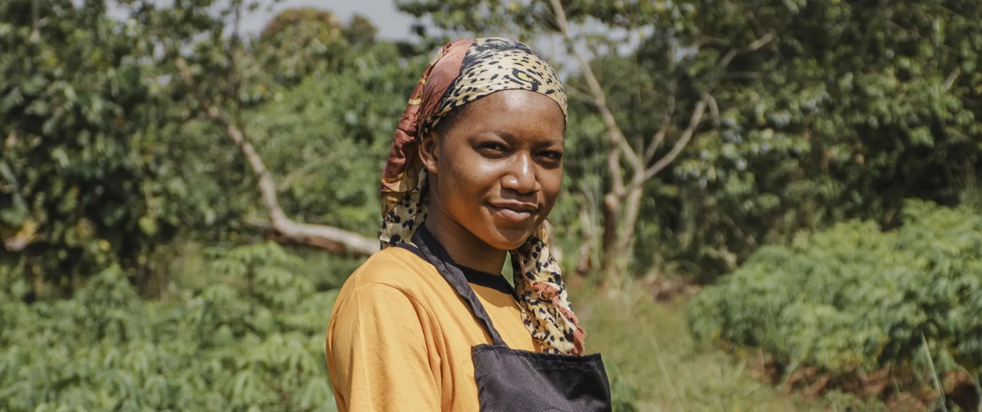 Woman farmer posing infront of a farm and smiling at the camera