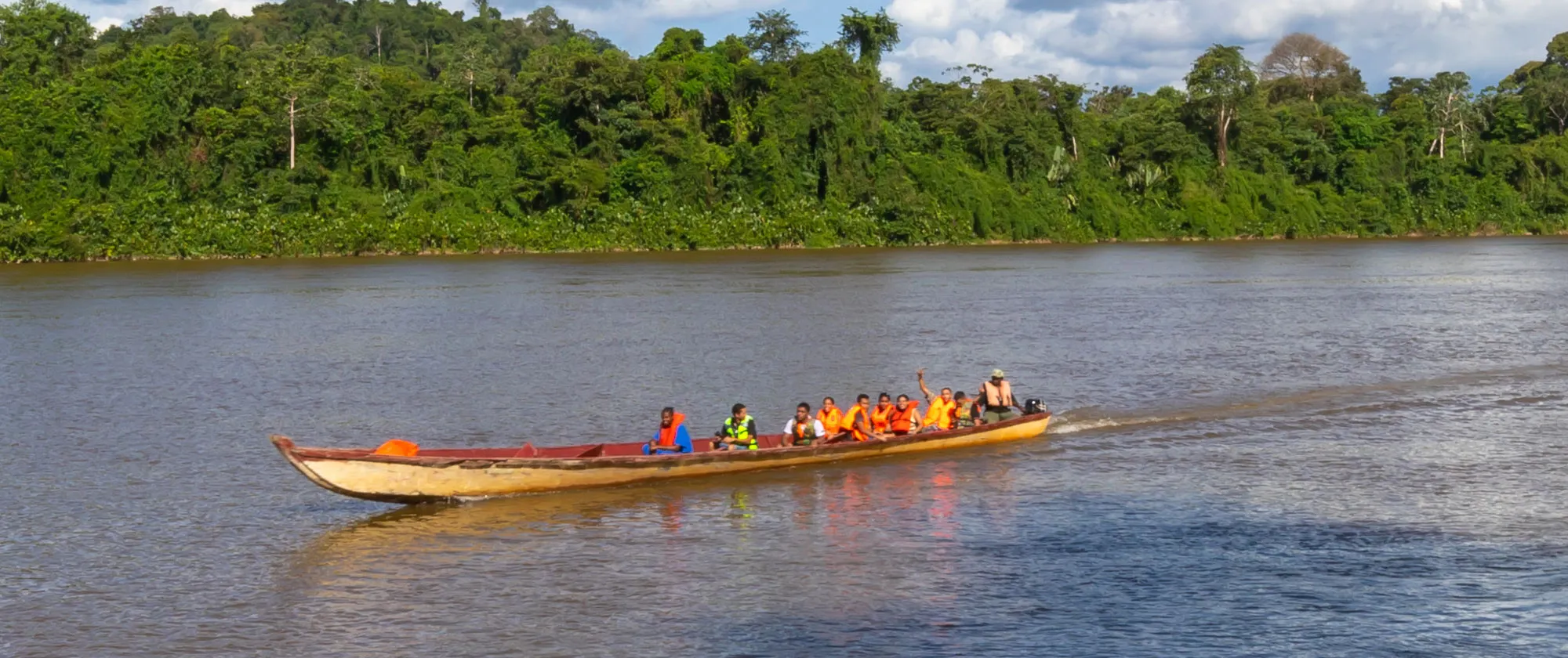 Tourists on a river in Paramaribo, Suriname in a traditional wooden boat wearing life jackets