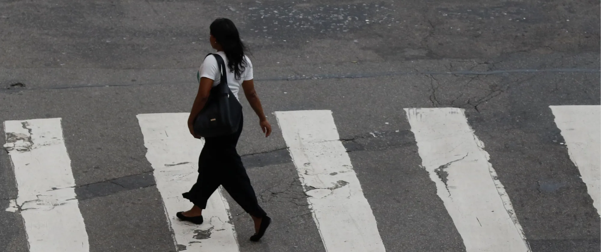 Mulher atravessa faixa de pedestres em uma rua não identificada no Rio de Janeiro
