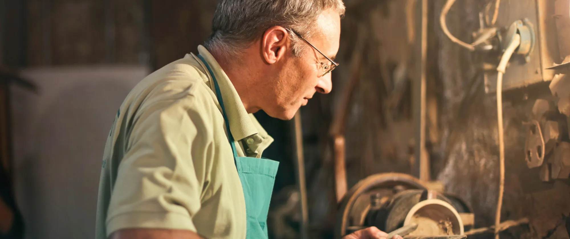 Senior male turner working on lathe machine in workshop