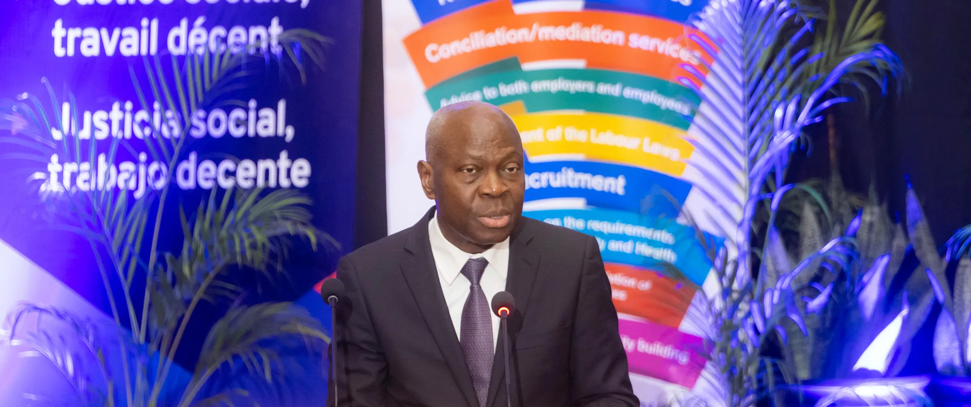  ILO Director-General speaking at the 13th ILO Meeting of Caribbean Ministers of Labour in Georgetown, Guyana, April 7, 2025, with banners and tropical plants in the background.