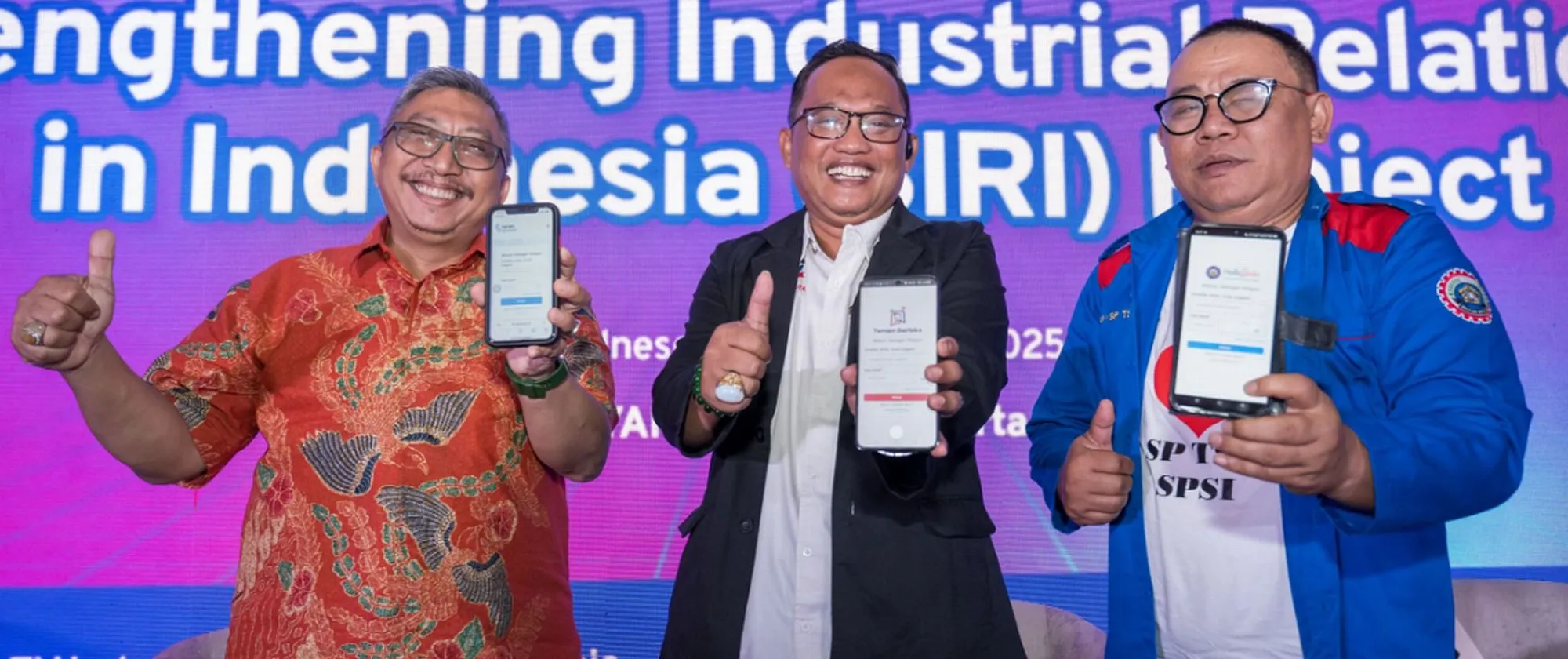 Three persons standing on the stage showing off their smartphones.