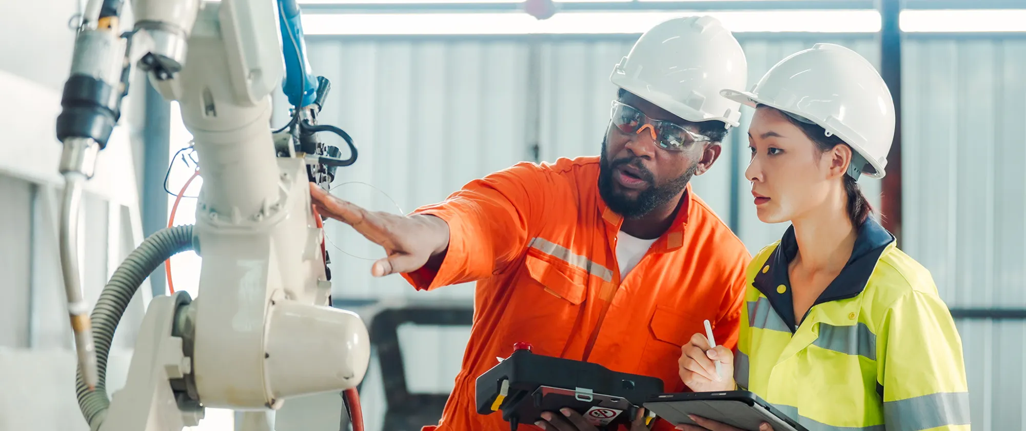 Engineer training a young employee in the use of robots
