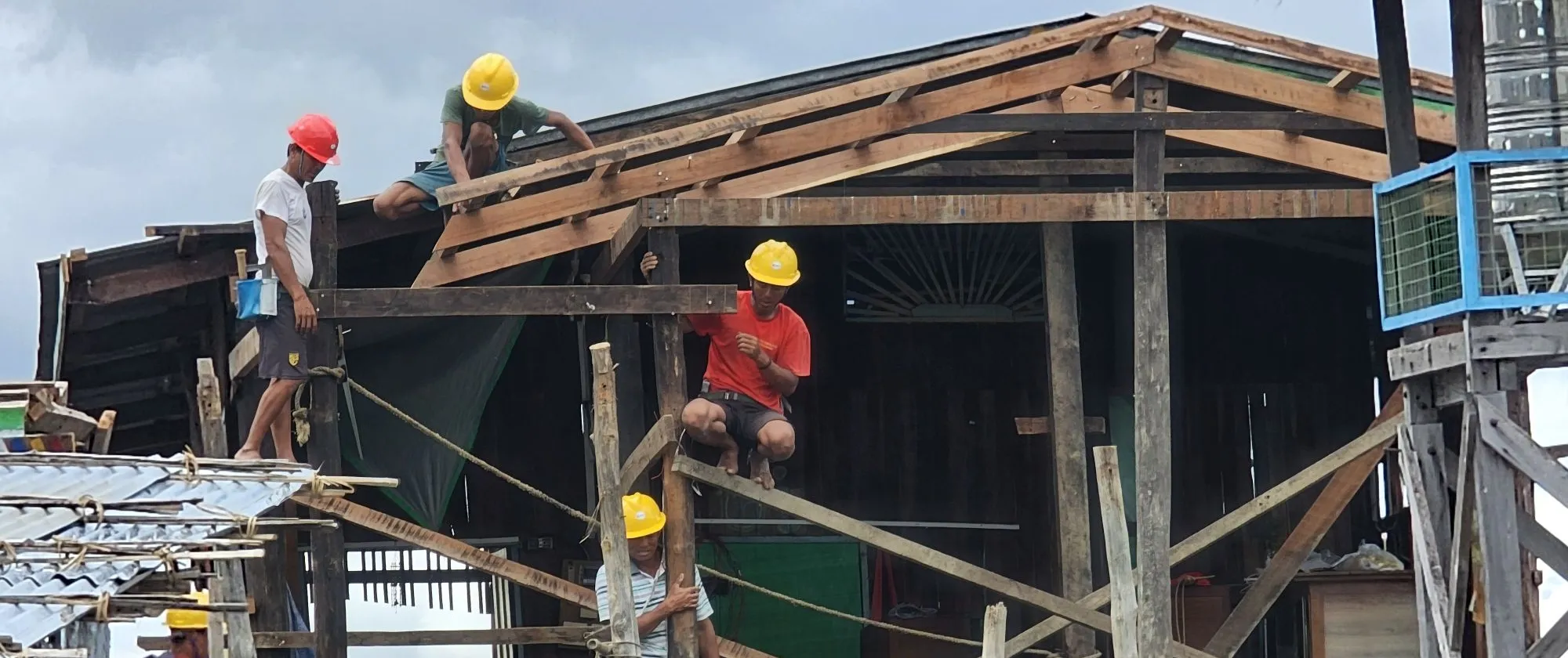 Community workers clearing debris from damaged house