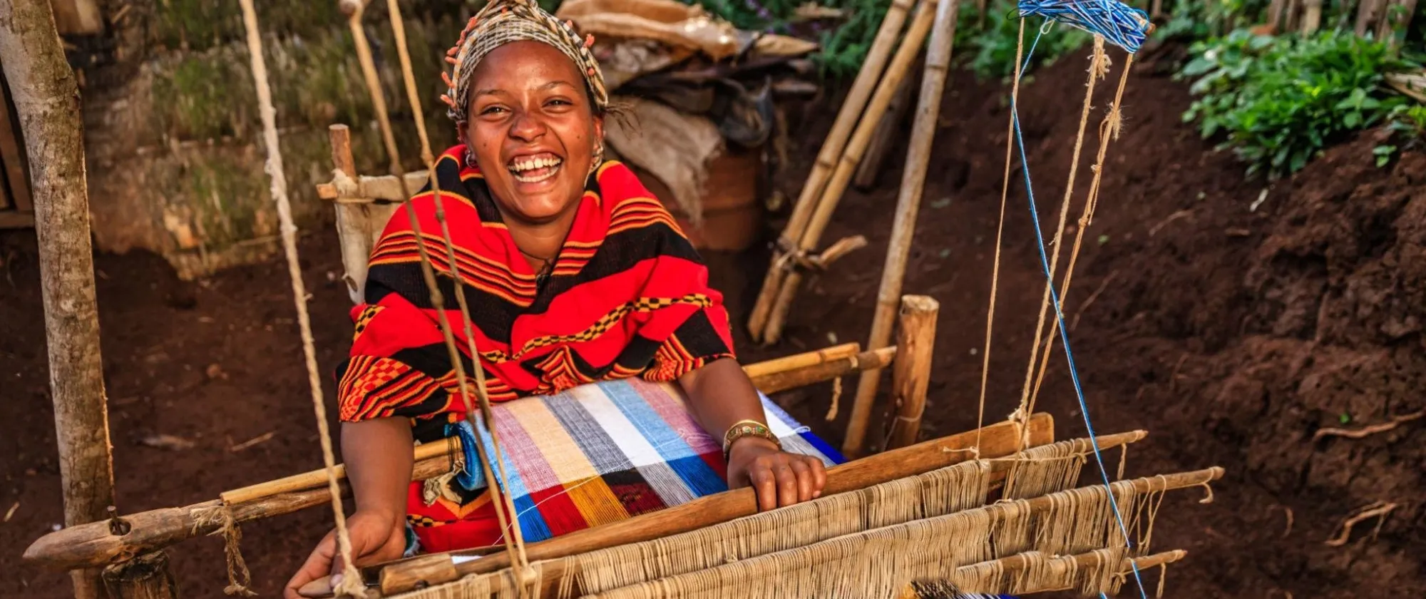 Woman weaving traditional attires and smiling at a camera
