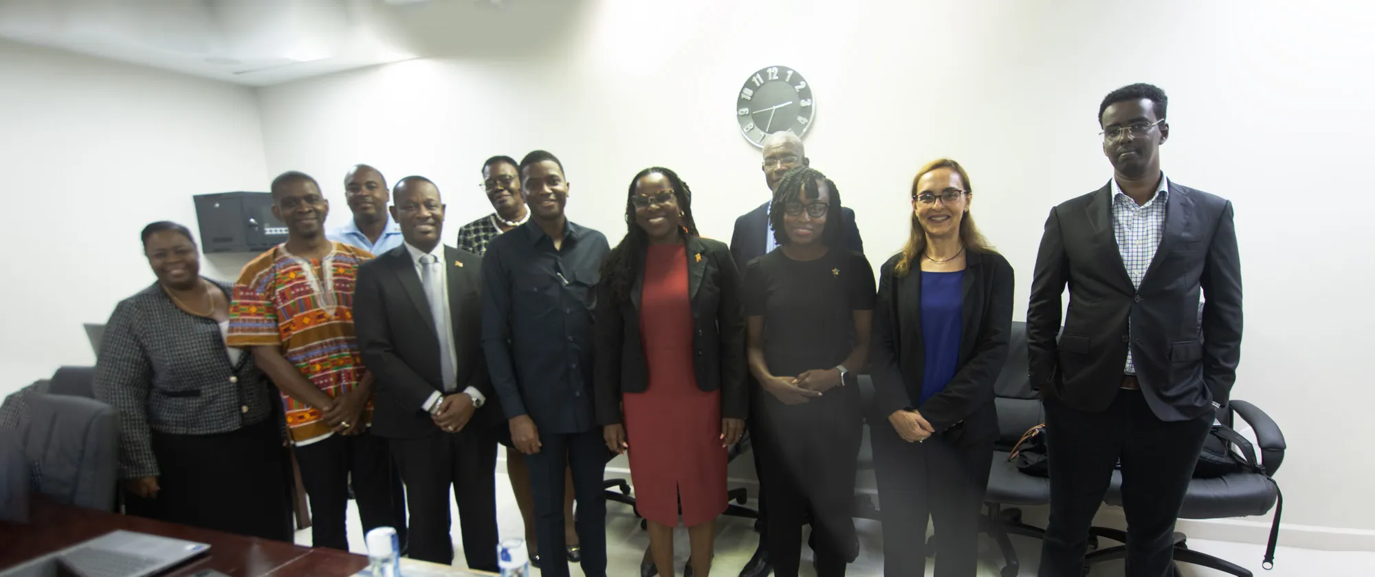 A group of ten individuals stands together in a conference room, dressed in a mix of business and business-casual attire.