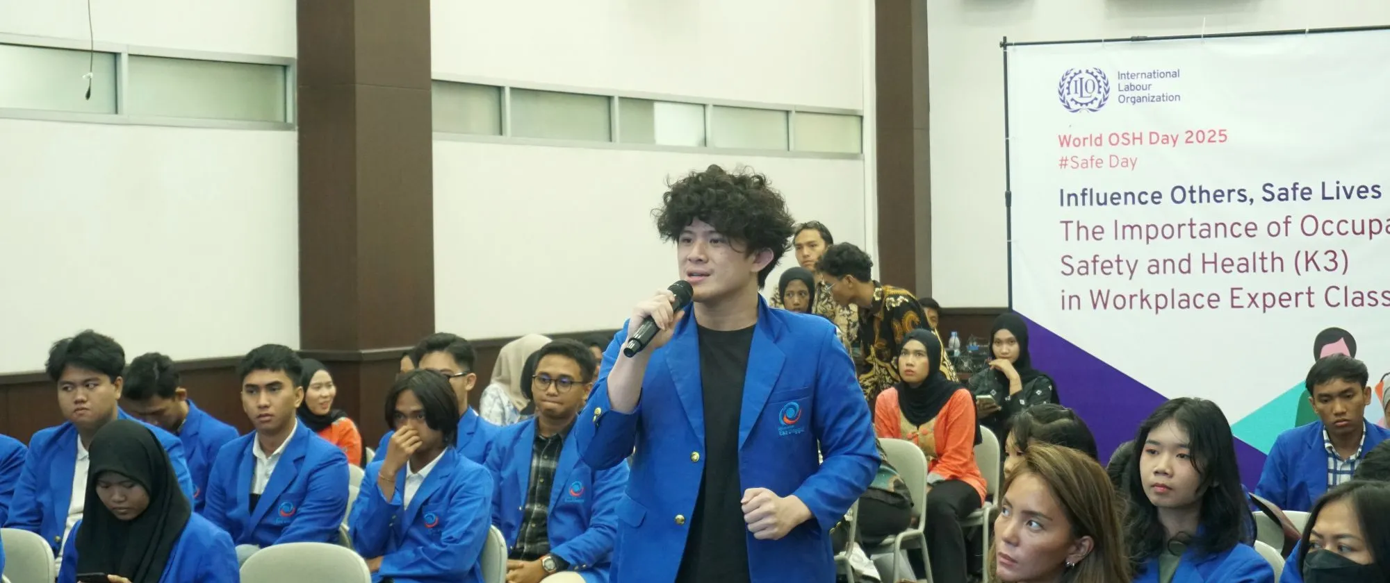A group of students joining a seminar with one student standing up holding a mic