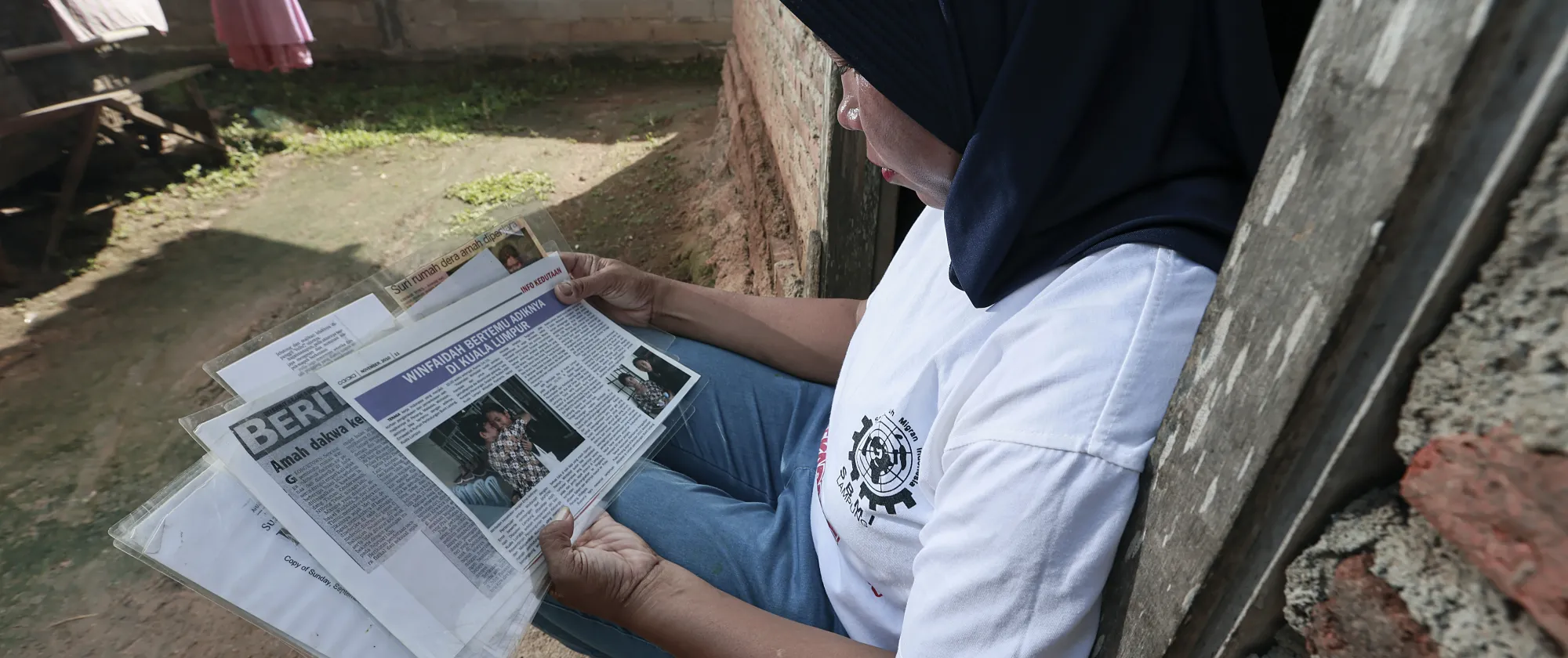 A woman is seating, reading press articles about her won story
