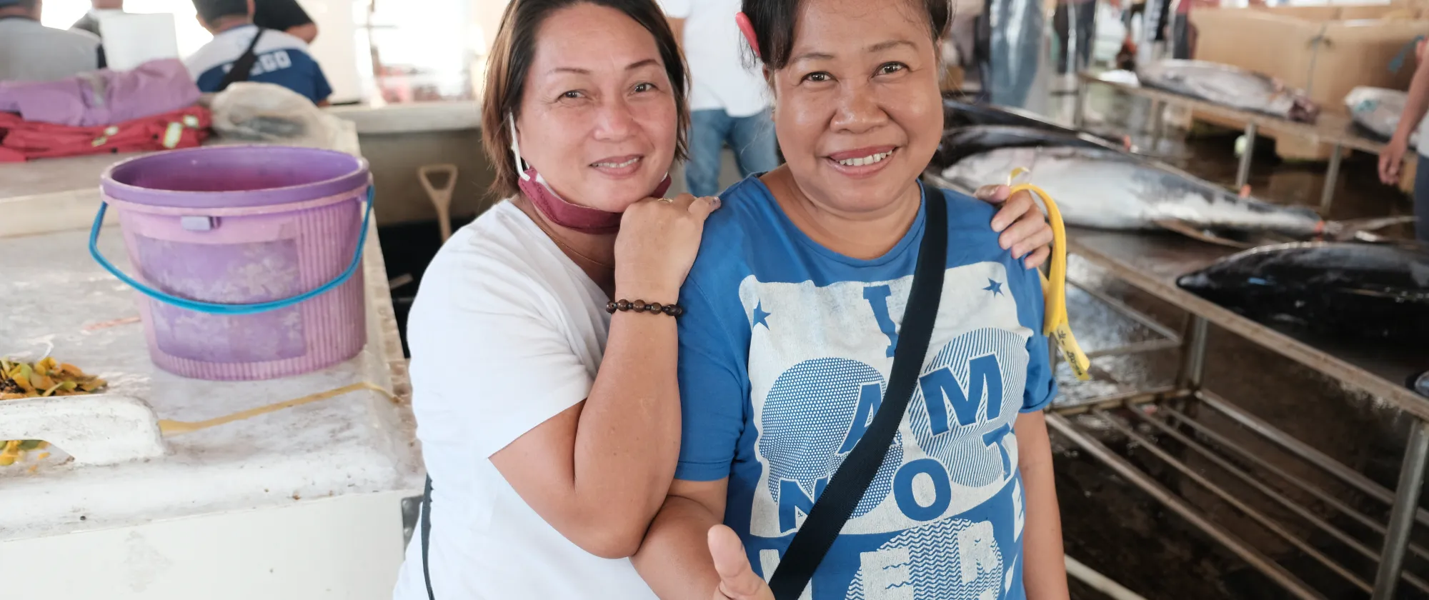 two women smiling at the camera at a covered fish market